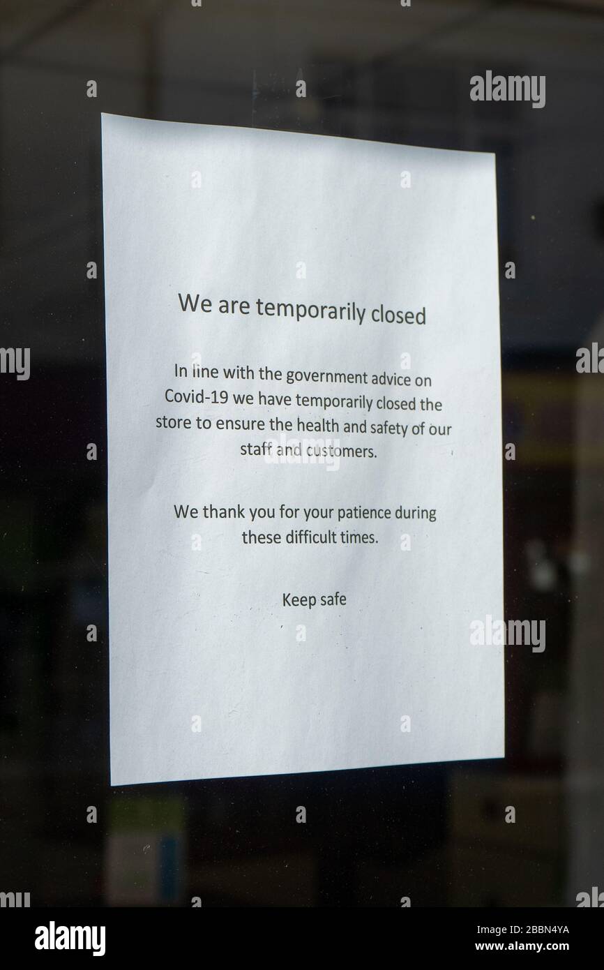 Un panneau dans la fenêtre d'un magasin indiquant qu'ils sont fermés en raison de Covid-19 ou de coronavirus Banque D'Images