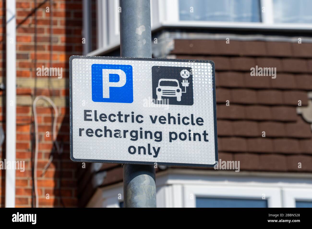 Un panneau sur un lampadaire indiquant qu'une baie de stationnement dans la rue est destinée à la recharge de véhicules électriques uniquement ou au point de charge de véhicules électriques Banque D'Images