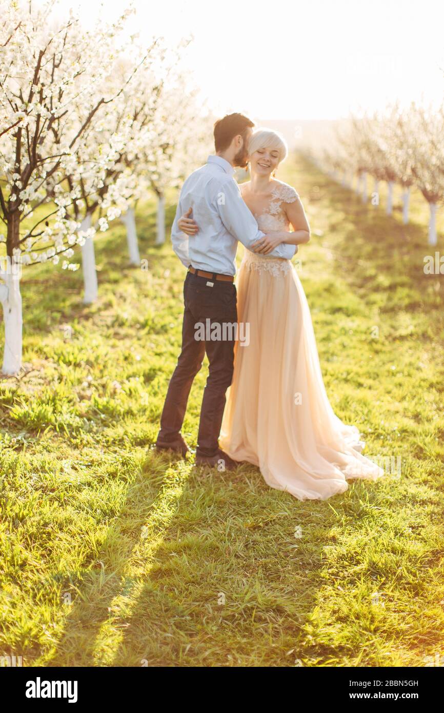 Charmant couple de mariage elegamment habille une fille dans une robe orange clair un homme dans une chemise blanche et un pantalon noir sont debout dans le jardin pres de la Photo