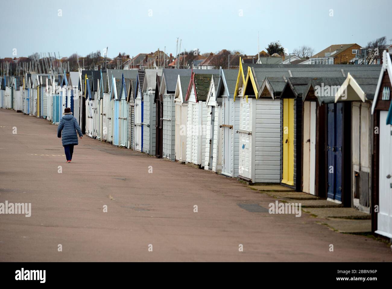 Une femme passe devant les huttes de plage sur la promenade de Southend, dans l'Essex, alors que le Royaume-Uni continue de se maintenir en place pour aider à freiner la propagation du coronavirus. Banque D'Images