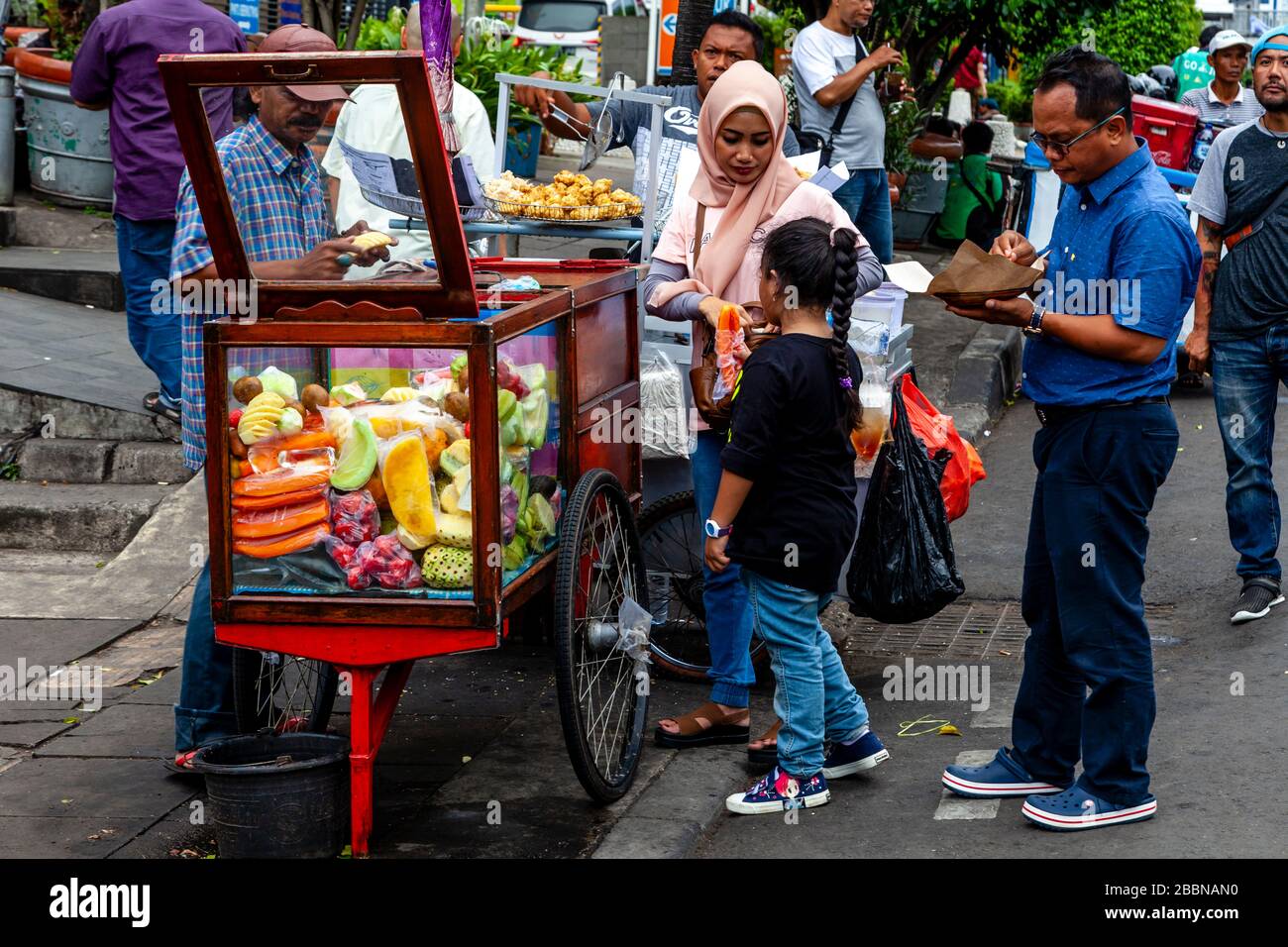 Une famille indonésienne achète des fruits frais d'UN Mobile Street Food Stall, Jakarta, Indonésie. Banque D'Images