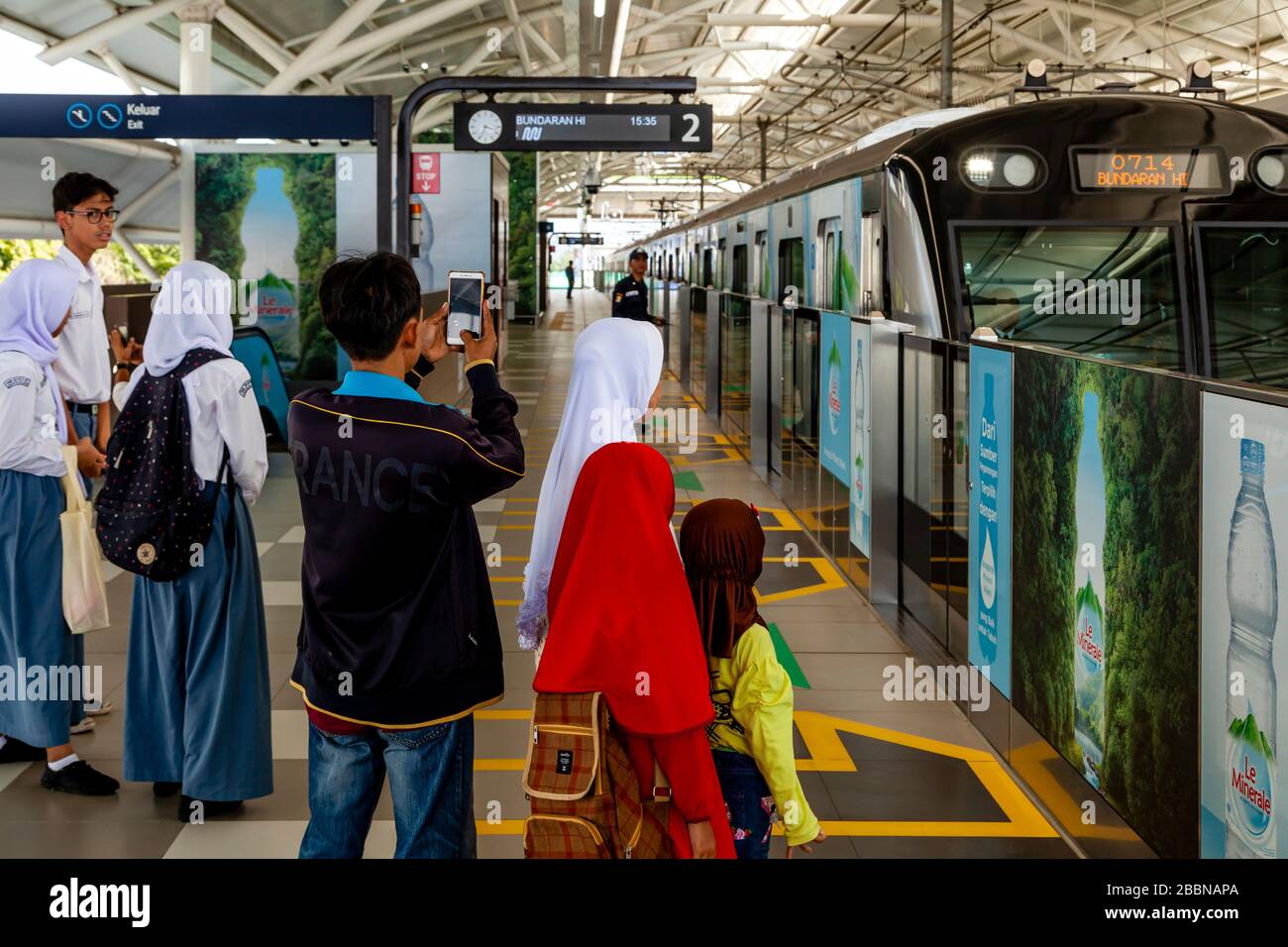 Une famille indonésienne attend sur la plate-forme de la gare comme un train approche, le métro (MRT), Jakarta, Indonésie. Banque D'Images
