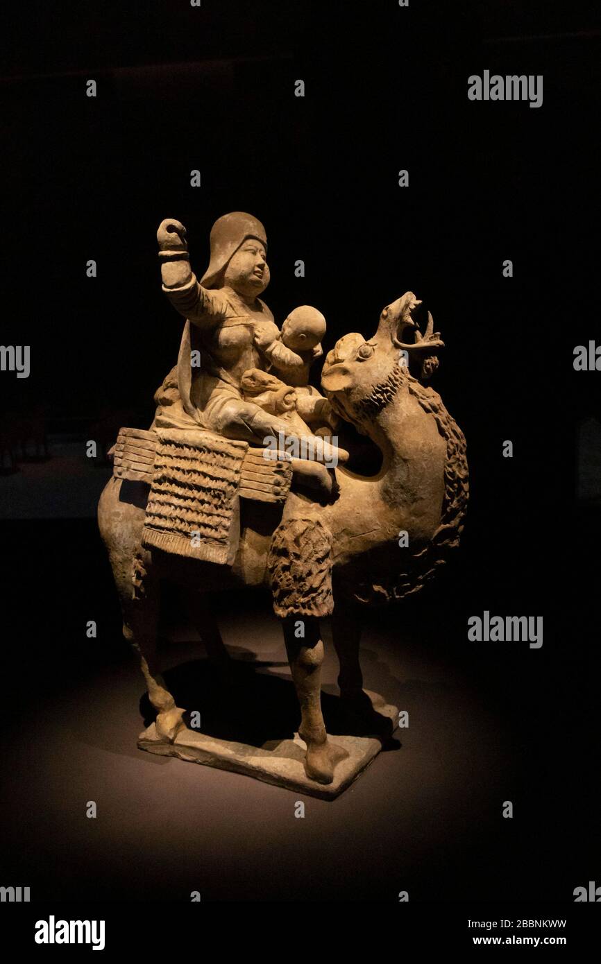 Figurine de poterie peinte de mère allaitant enfant tout en faisant du cheval à dos de chameau, dynastie Tang (618-907), Musée d'art Aurora, Shanghai, Chine Banque D'Images