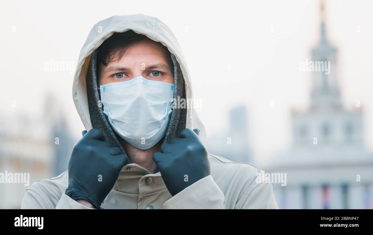 Portrait gros plan jeune européen homme dans un masque médical jetable de protection marchant à l'extérieur. Nouveau coronavirus (COVID-19). Concept de soins de santé Banque D'Images