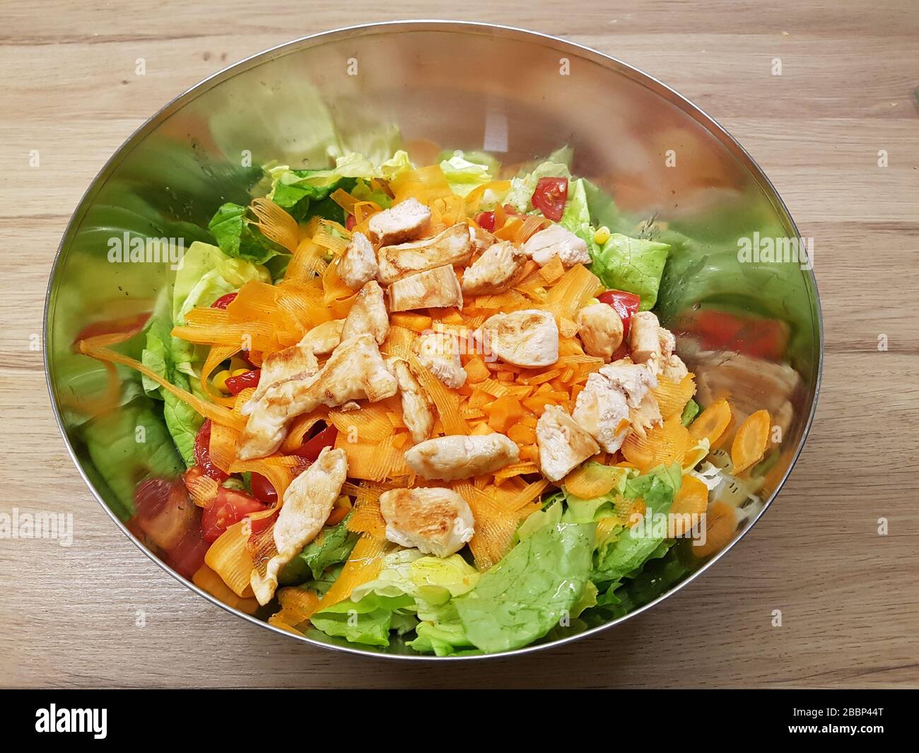 Bol de salade de laitue verte mélangée et fond en bois avec tranches de légumes et légumes carottes, tomate , morceaux de poulet rôtis - léger , sain Banque D'Images