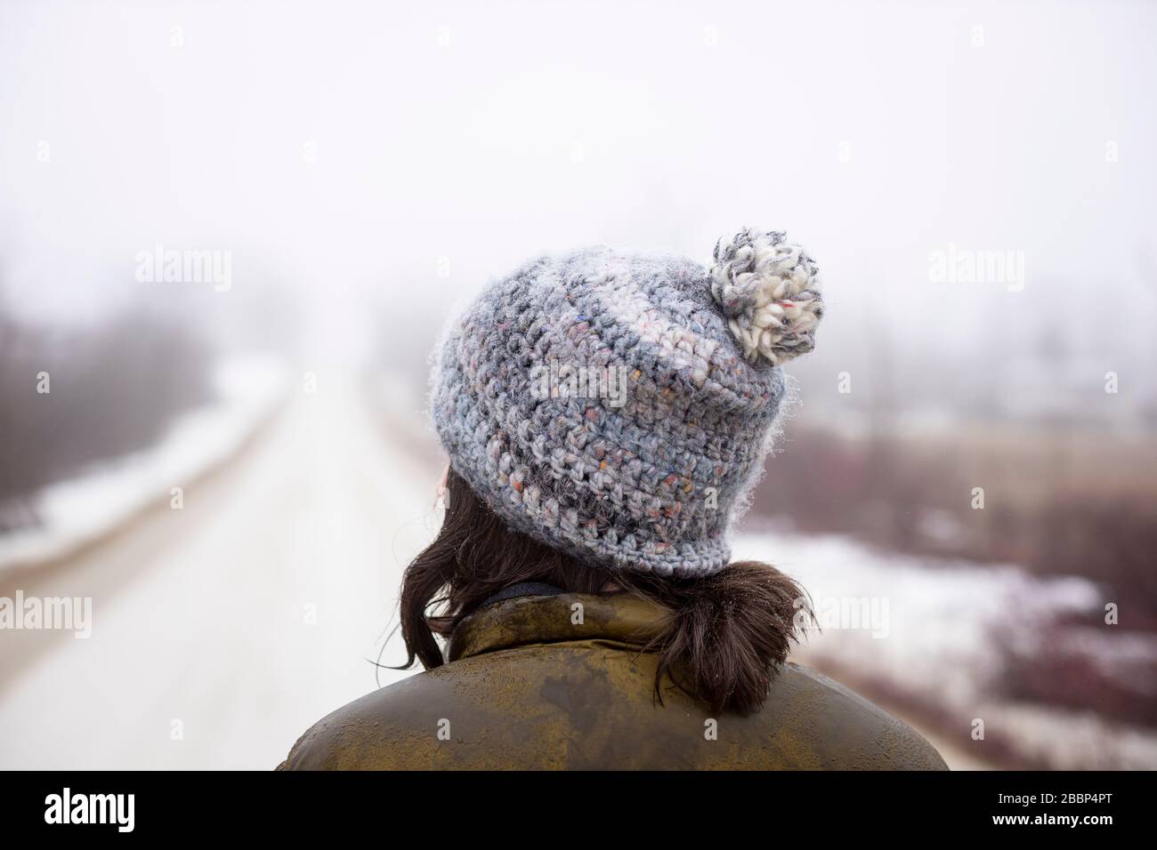 Une dame marche seule sur une route de gravier pendant la réglementation d'urgence concernant le coronavirus / COVID-19, sur une journée de printemps froid brumeuse. Banque D'Images