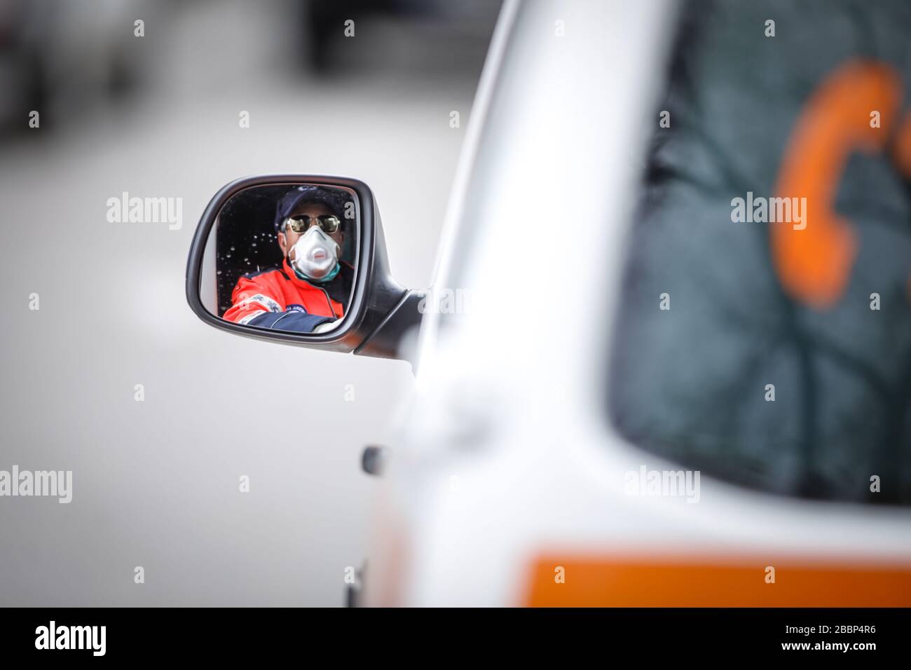 Bucarest, Roumanie - 1er avril 2020 : conducteur d'ambulance vu dans le rétroviseur latéral du véhicule. Banque D'Images