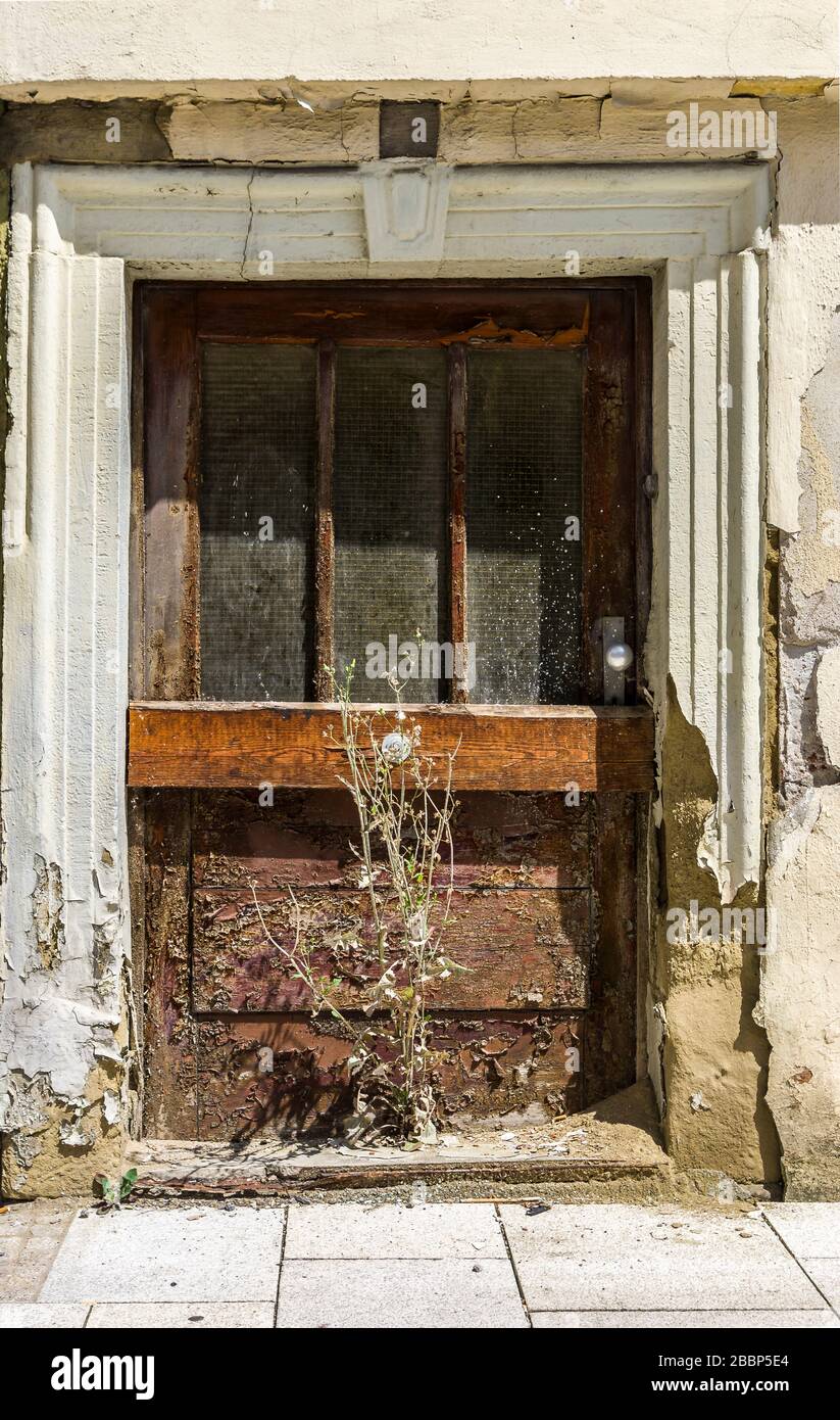 Porte d'une maison abandonnée, délabrée et de mauvaises herbes qui poussent devant la porte Banque D'Images