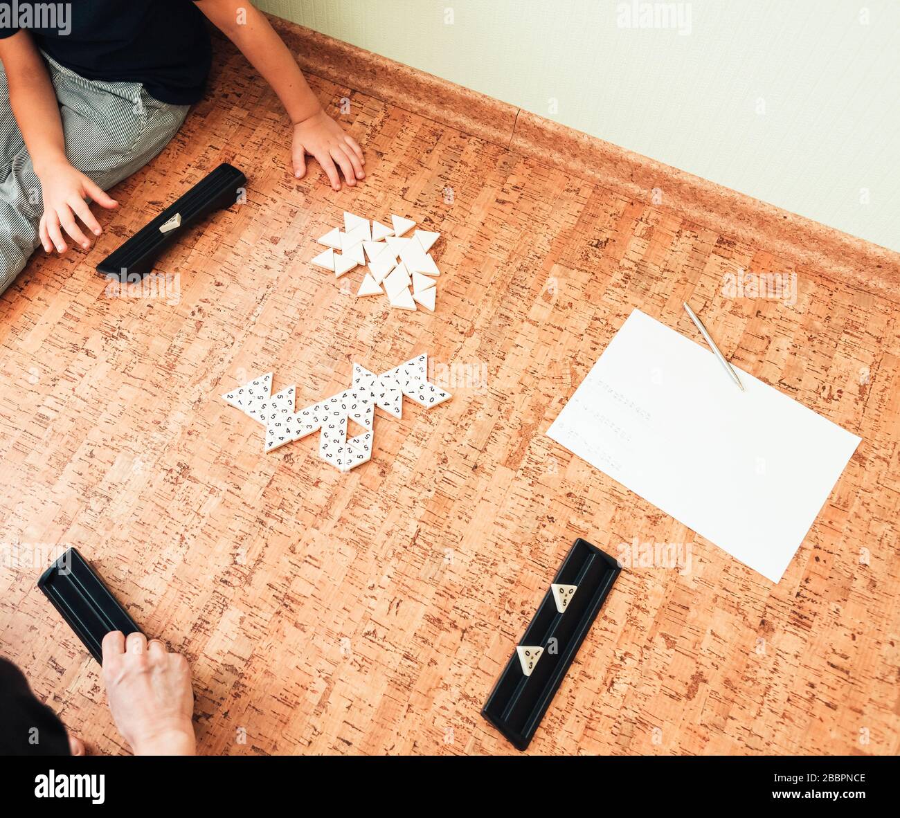 La famille joue le sol dans un jeu de table de trimino. Vue de dessus. Développement du jeu Banque D'Images