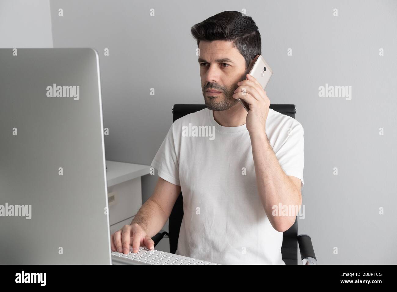 un homme parle sur le téléphone qui travaille à la maison Banque D'Images