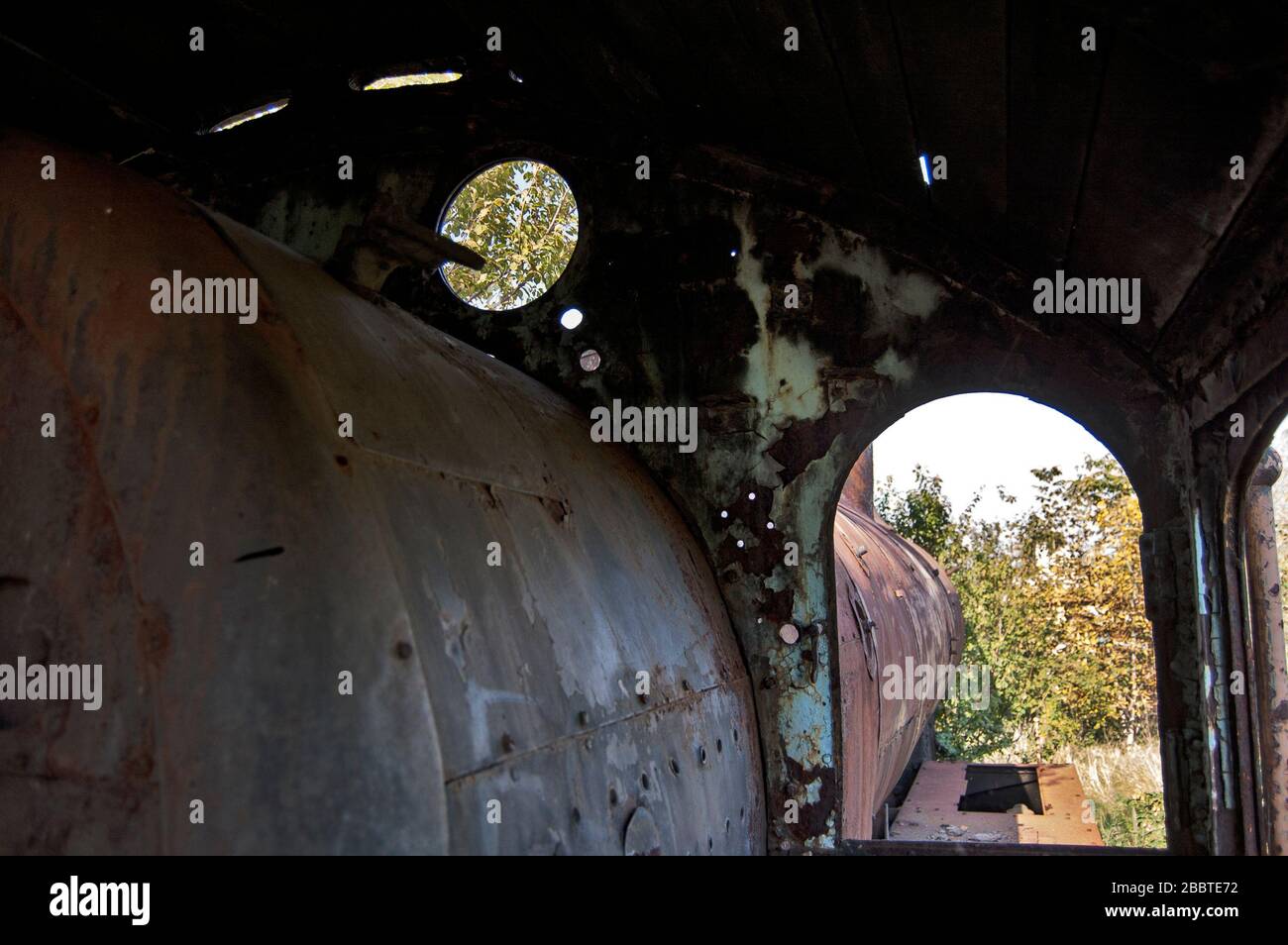 Ancienne locomotive à vapeur de chemin de fer dysfonctionnelle qui est surcultivée avec des mauvaises herbes. Banque D'Images