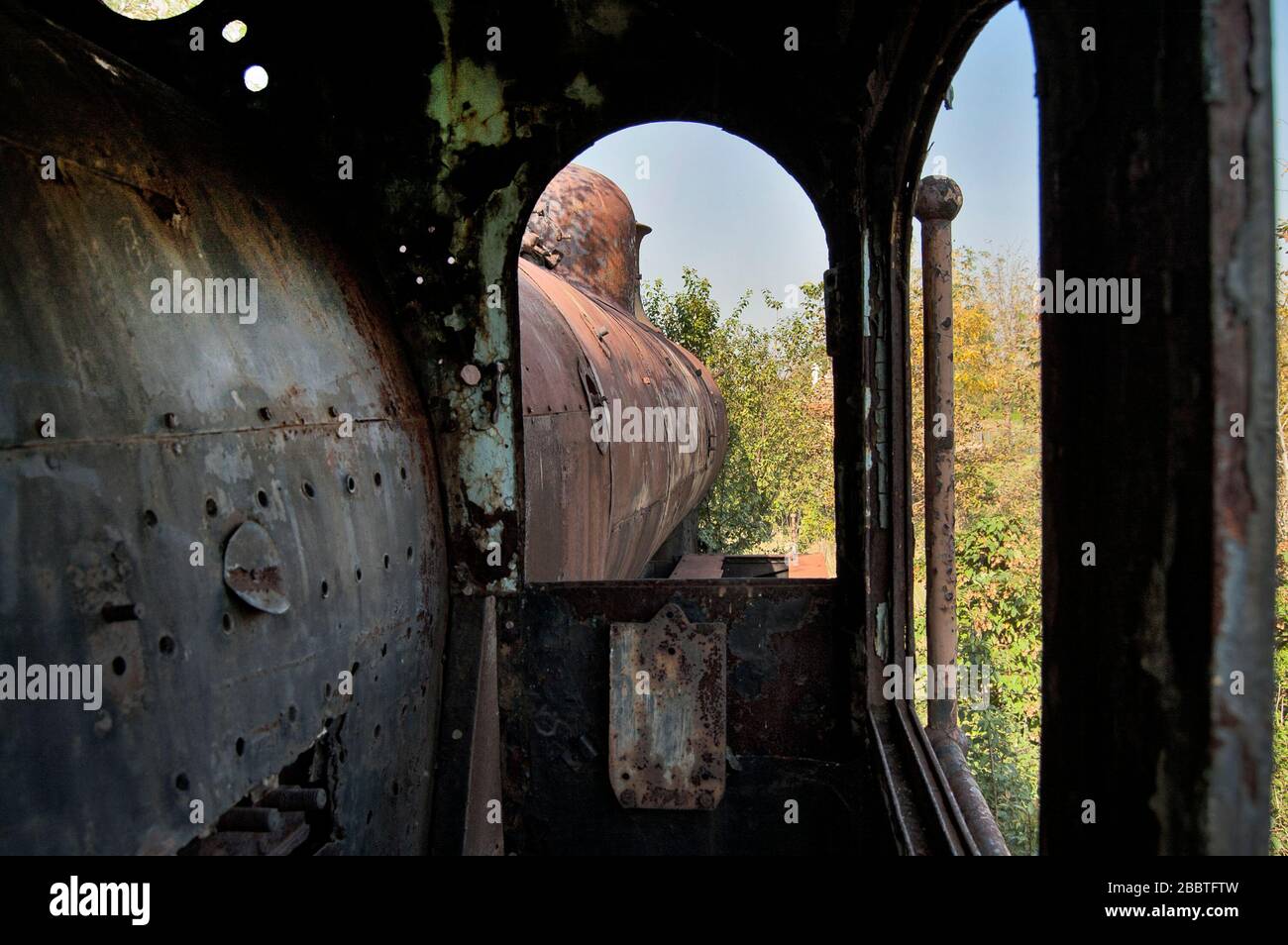 Ancienne locomotive à vapeur de chemin de fer dysfonctionnelle qui est surcultivée avec des mauvaises herbes. Banque D'Images