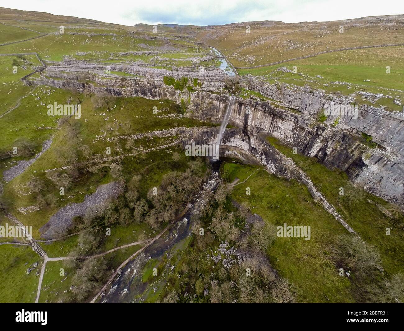 L'eau coule au-dessus de Malham Cove. Le 6 décembre 2015, après une période de forte pluie, Malham Cove devient temporairement la plus haute chute libre du Royaume-Uni. Vue aérienne sur la drone montrant la falaise de calcaire verticale de 80 m au cœur du parc national du Yorkshire Dales a été formée au dernier âge de glace, mais l'eau n'a pas été vue en cascade de son bord dans la mémoire vive (voir « informations supplémentaires ») © Ian Wray /Alay Banque D'Images