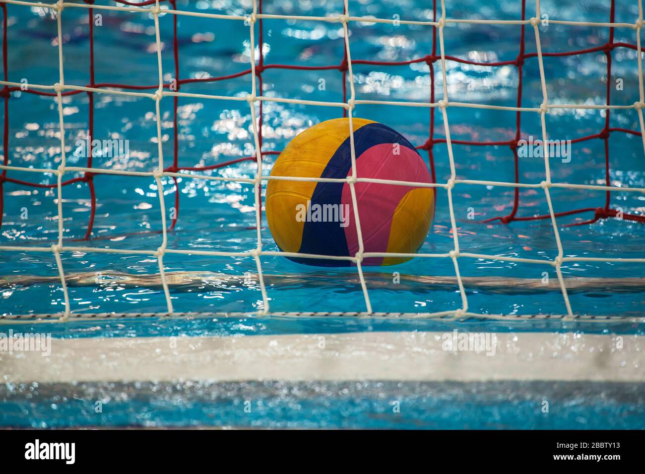 Ballon de water-polo flottant sur l'eau de la piscine bleue Banque D'Images