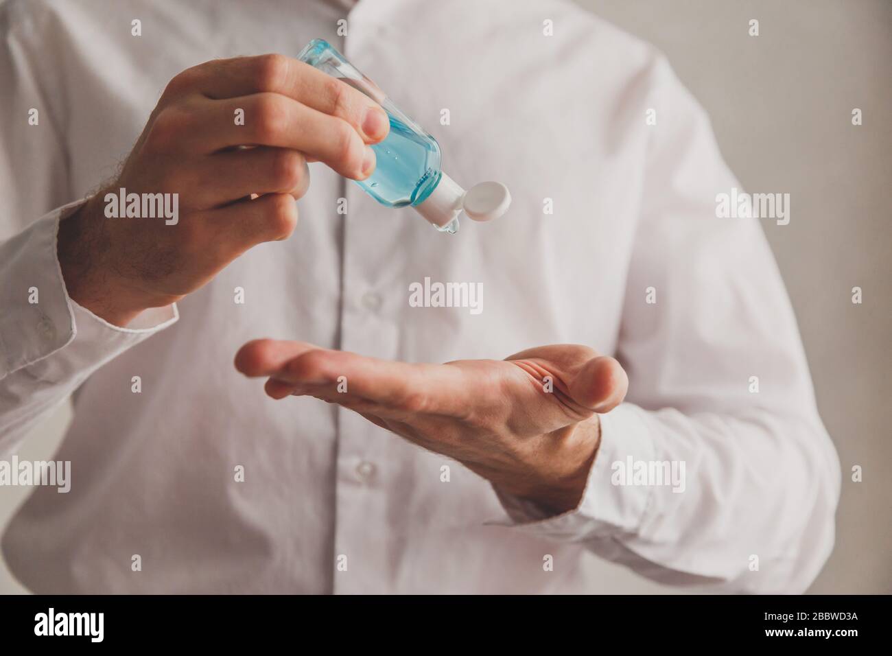 Homme en chemise blanche à l'aide d'un distributeur de gel désinfectant pour les mains, coronavirus Covid-19 dans les lieux publics. Concept d'antiseptique, d'hygiène et de soins de santé Banque D'Images
