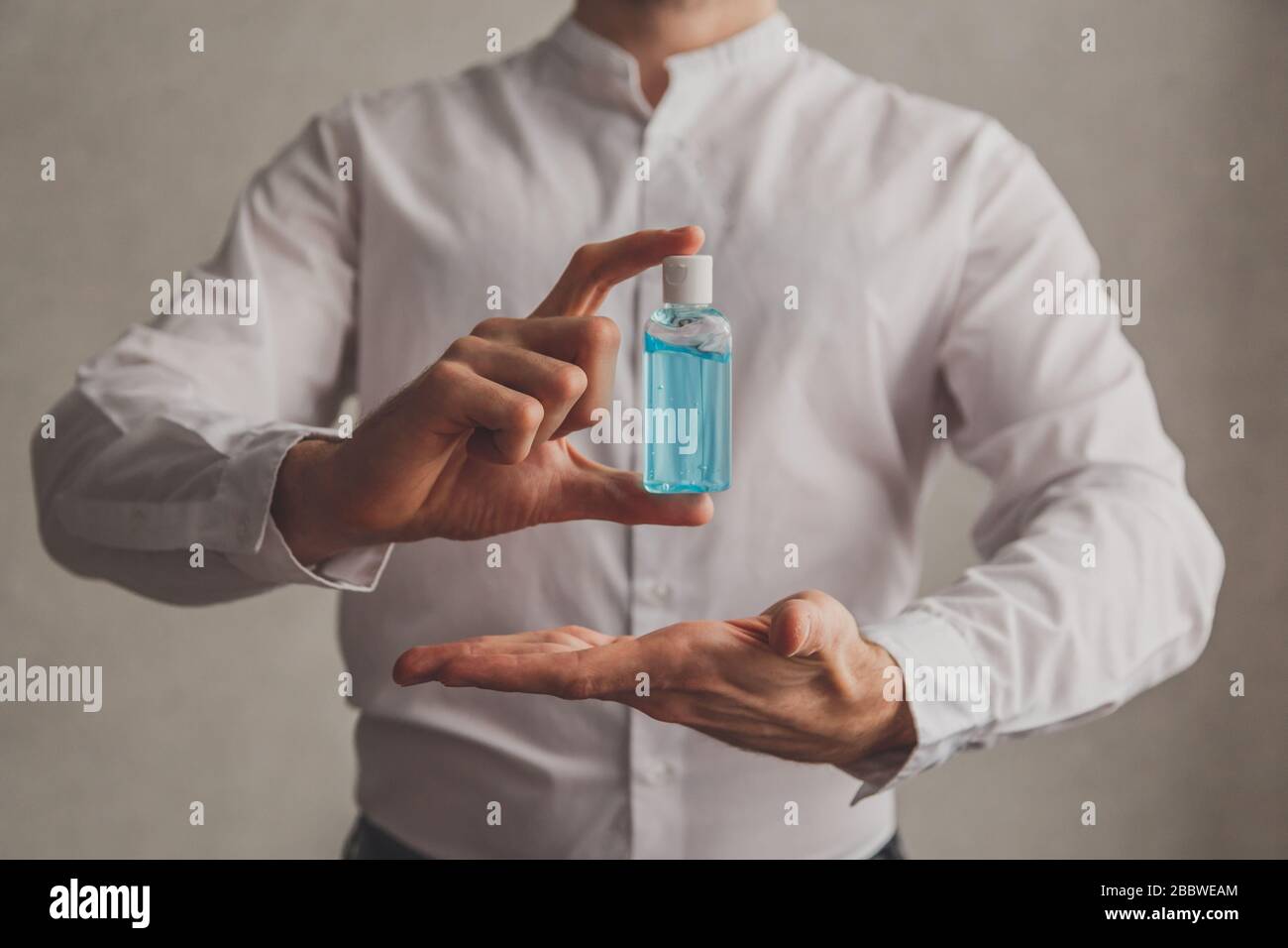 L'homme dans une chemise blanche contient de l'aseptisant pour gel d'alcool. Mise au point sélective. Banque D'Images