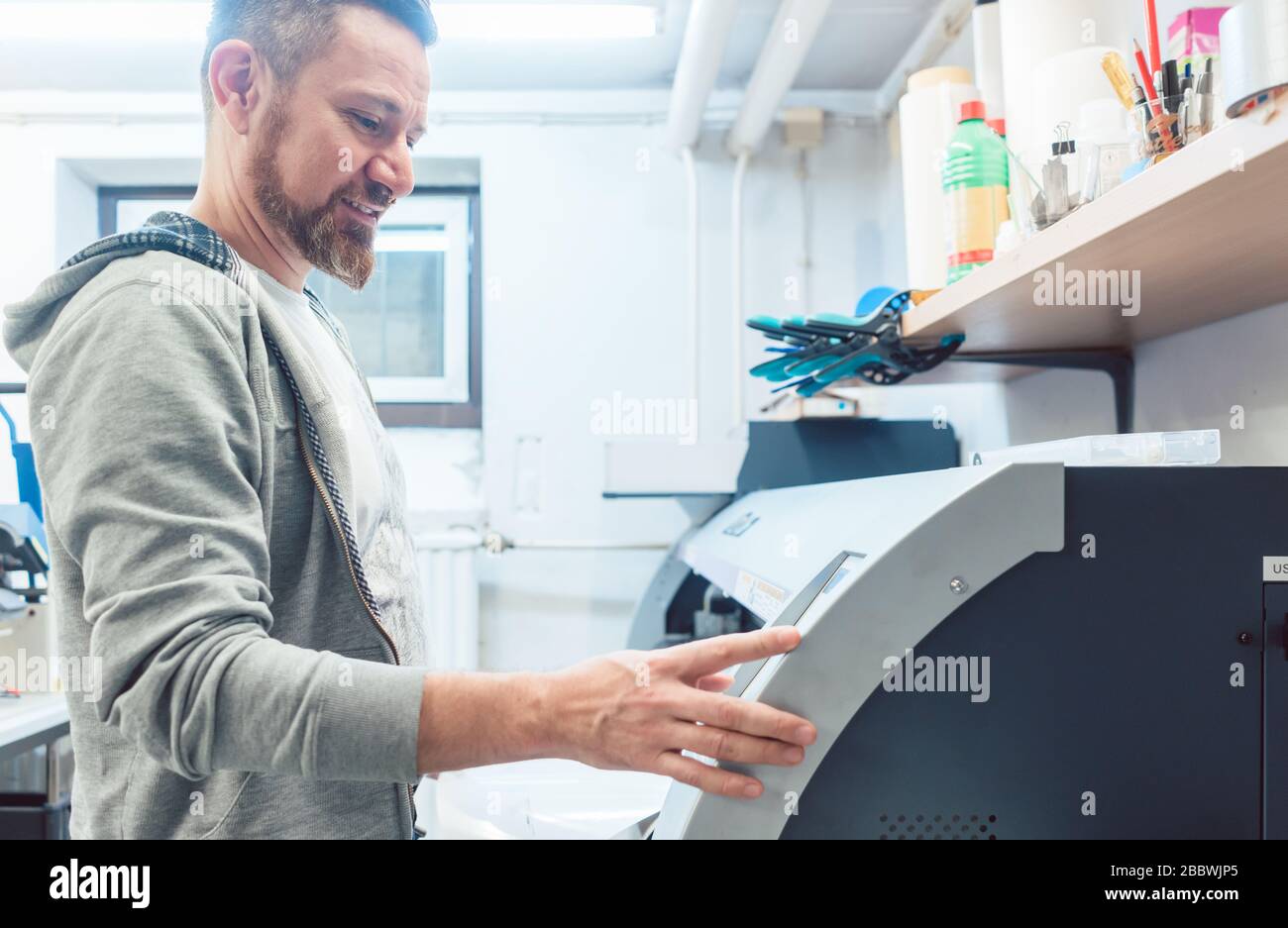 L'homme travaillant sur l'imprimante grand format en agence de publicité Banque D'Images