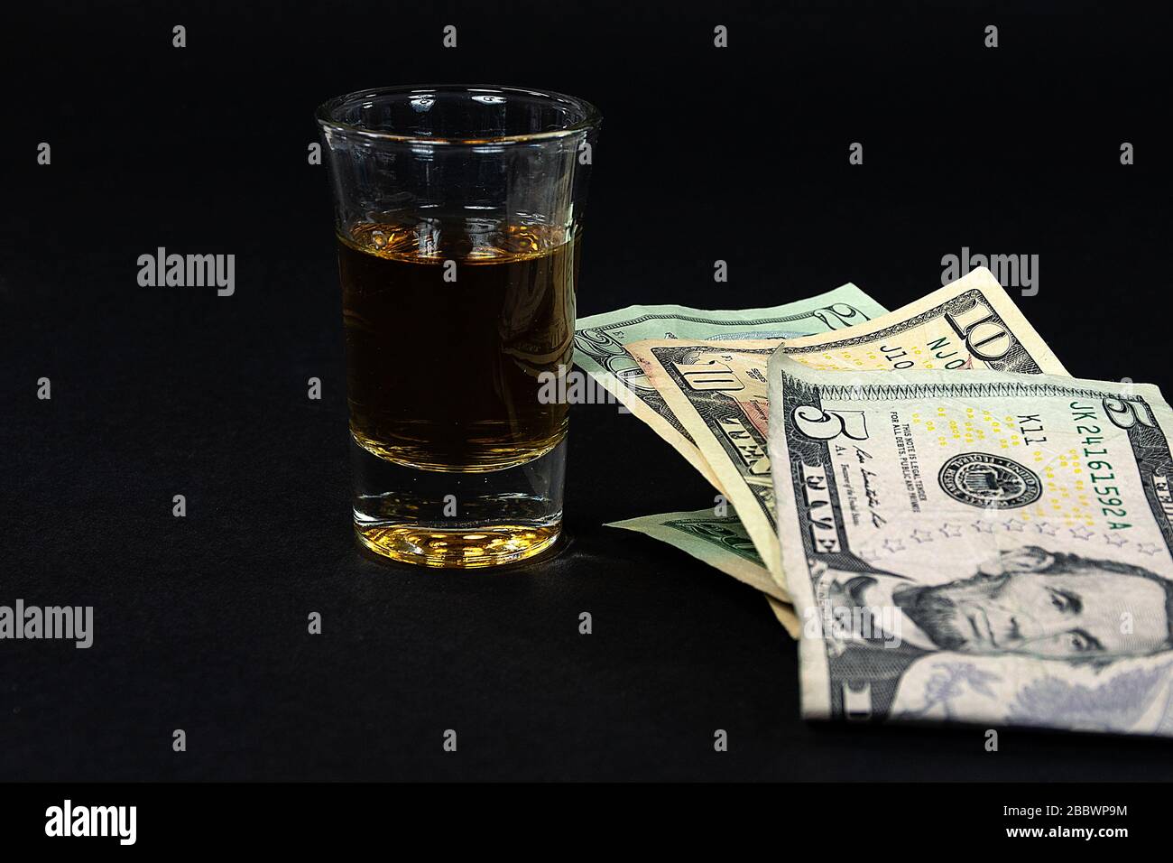 Gros plan sur l'argent américain plié et coup de whisky sur le noir Banque D'Images