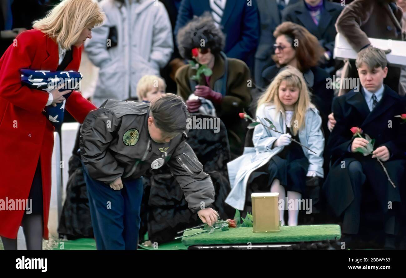 Arlington Virginia, États-Unis, 15 février 1991 funérailles du capitaine de marine Jonathan Edwards la première victime de l'opération tempête du désert à être enterrée au cimetière national d'Arlington. Sa veuve Gayle, (en manteau rouge) aide son fils Bennett, 11 pose une fleur sur la tombe de son père pendant les funérailles Banque D'Images