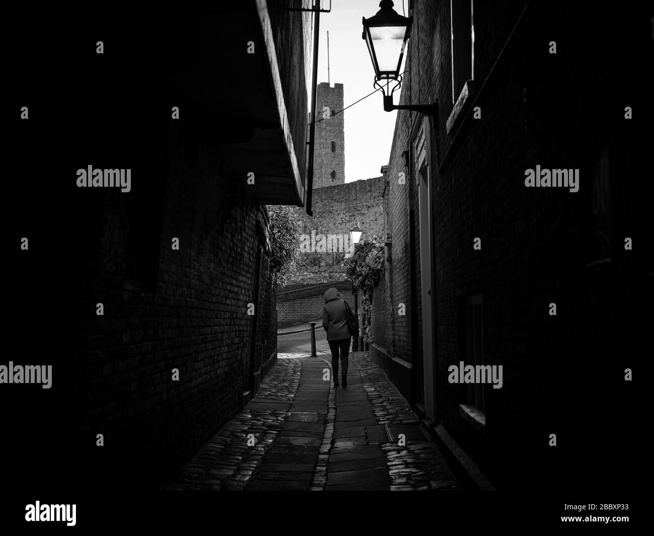 Une femme seule descend une ruelle dans la ville historique de Rochester pendant le maintien de la COVID-19 dans le Kent, en Angleterre. Banque D'Images