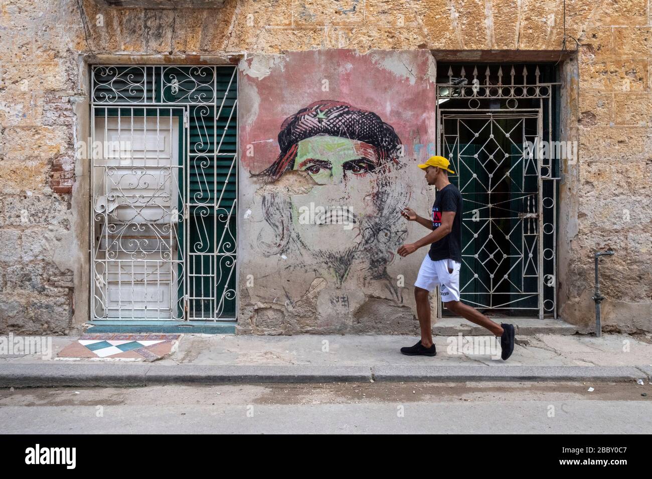 Jeune homme marchant par la peinture murale d'art de la rue, la vieille Havane Banque D'Images