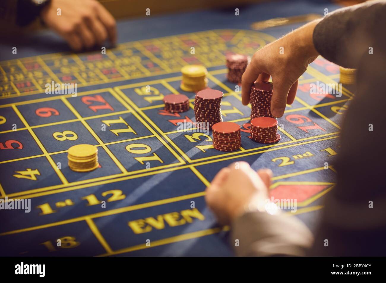 Gros plan des mains avec des jetons pour jouer sur une table de roulette de casino. Banque D'Images