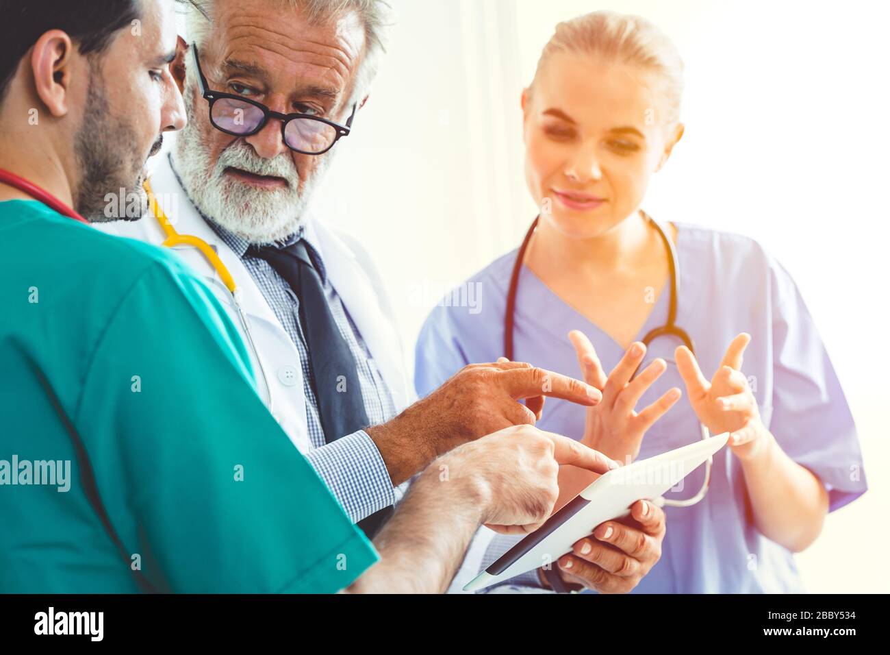 Discussion de l'équipe médicale du médecin sur le dossier patient à l'aide de la tablette ou de l'écran du moniteur de l'ordinateur de poche. Banque D'Images