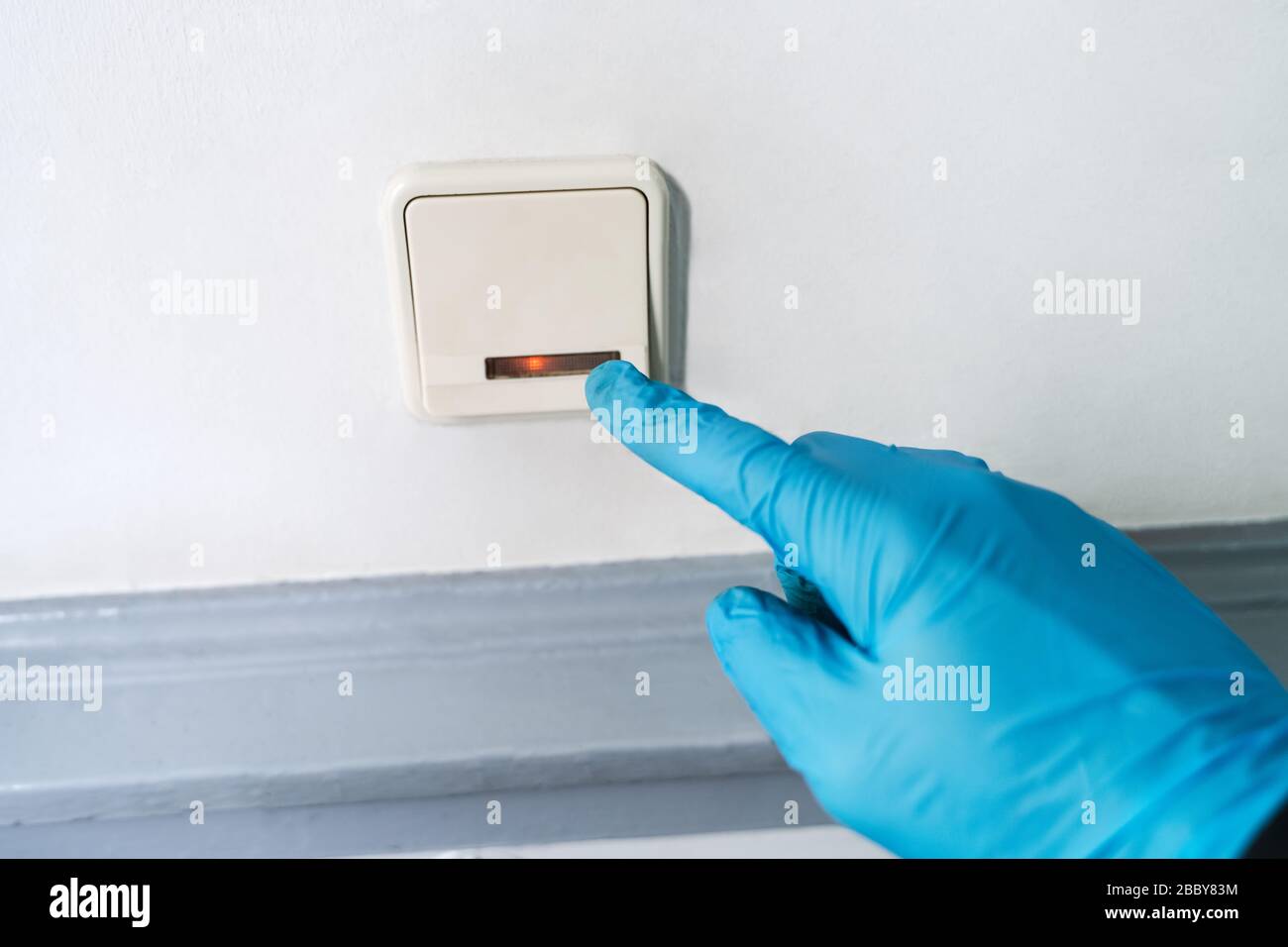 Homme utilisant des gants pour appuyer sur le bouton pour se protéger de l'infection par le coronavirus Banque D'Images
