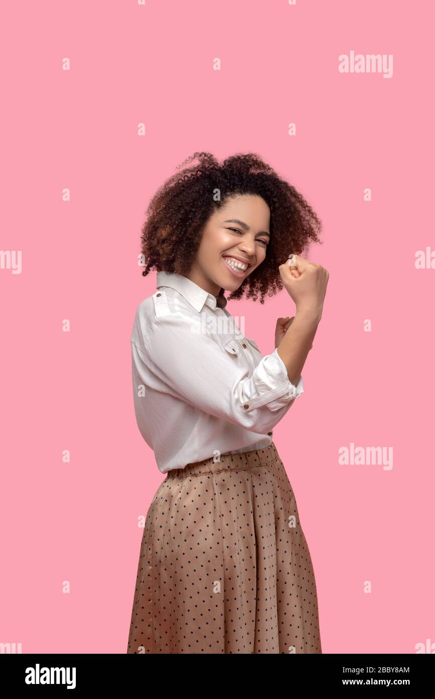 Femme dans une jupe et une chemise debout sur le côté avec des poings. Banque D'Images