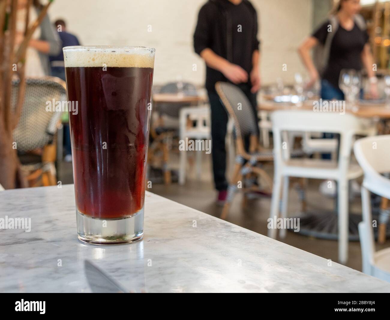 Bière sombre assise sur la table au restaurant avec les convives assis Banque D'Images