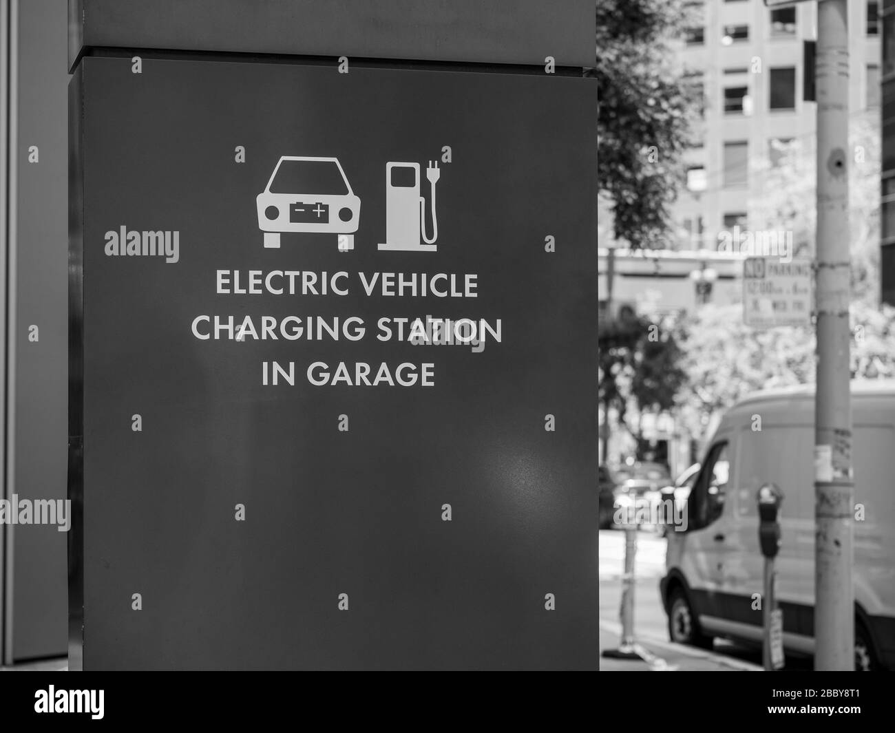 Station de charge de véhicule électrique dans le symbole de garage et panneau affiché à l'extérieur sur la rue Banque D'Images