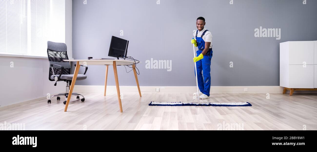 Homme Avec Balai À Franges Et Panneau De Sol Humide Banque D'Images