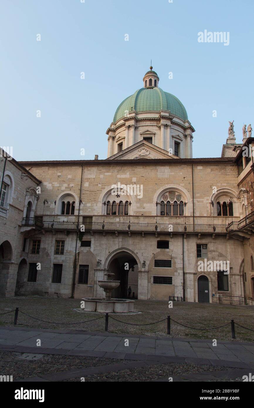 Brescia, Italie - 1 août 2018: La vue de la fontaine dans la cour intérieure du palais médiéval Palazzo del Broletto avec dôme de la nouvelle cathédrale sur b Banque D'Images
