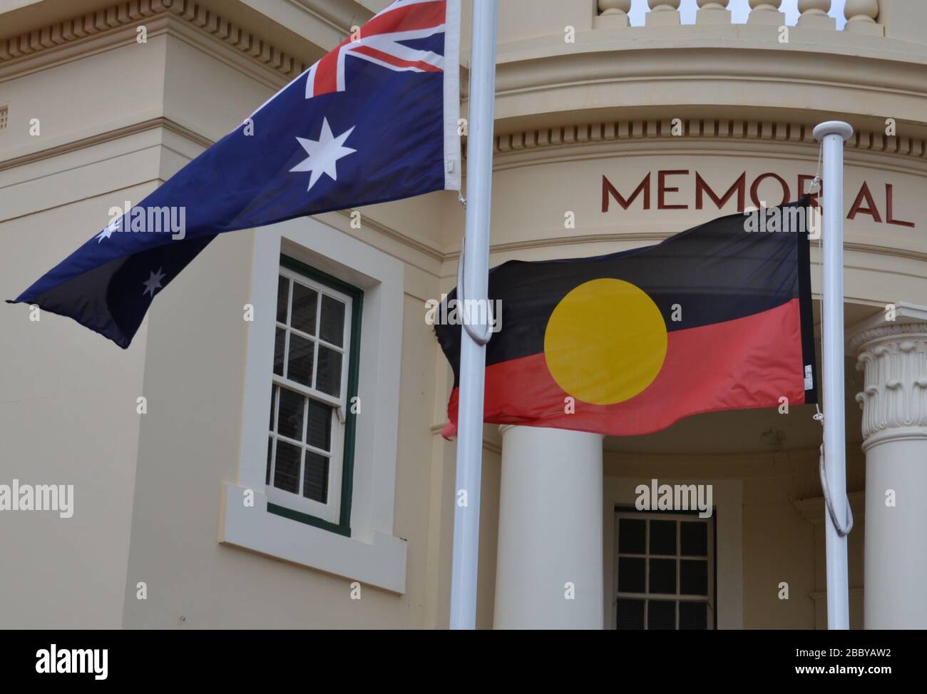 Drapeau aborigène volant le long du drapeau national australien en dehors d'une salle commémorative dans la ville régionale Banque D'Images