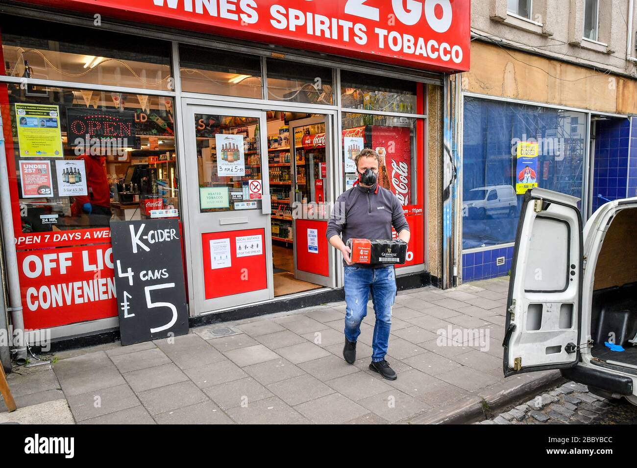 Un homme portant un masque porte un cas d'alcool à Southville, Bristol, alors que le Royaume-Uni continue de se maintenir en place pour aider à freiner la propagation du coronavirus. Banque D'Images