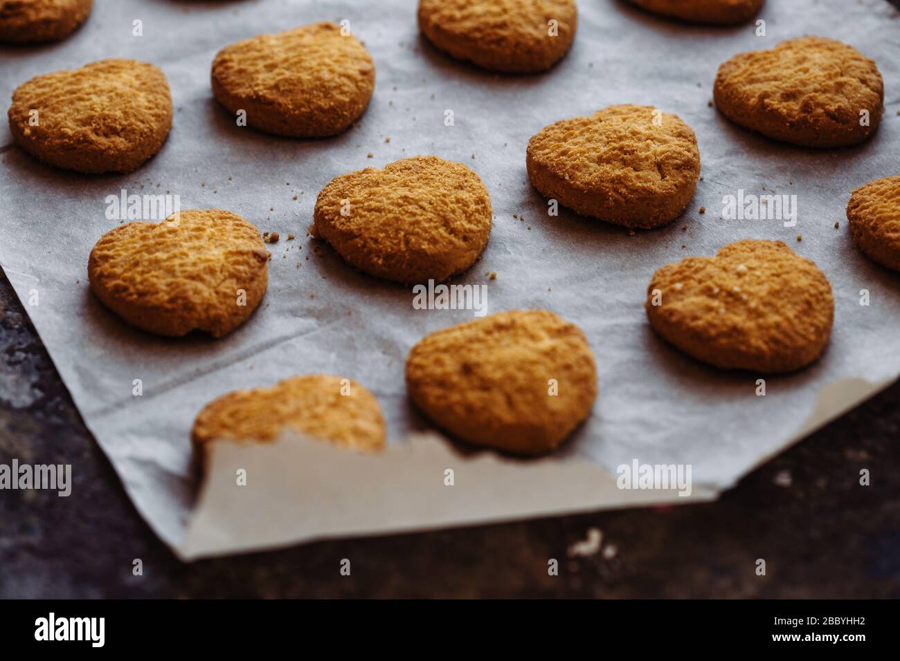 Petits gâteaux frais en forme de coeur sur papier parchemin. Banque D'Images
