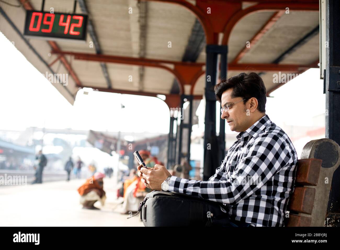 Homme utilisant le téléphone en attendant à la plate-forme de la gare Banque D'Images