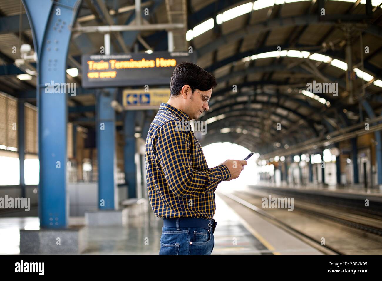 Homme utilisant le téléphone mobile à la plate-forme de la gare Banque D'Images