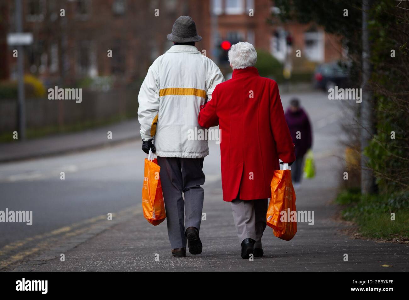 Les personnes âgées couple marchant à la maison avec des sacs de shopping pendant le verrouillage de la pandémie de virus de Corona. Banque D'Images