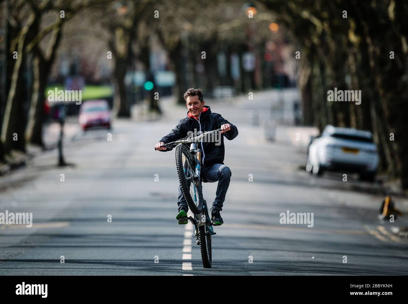 Cycliste fait une roue dans une rue calme de Glasgow, pendant le verrouillage du virus Corona. Banque D'Images