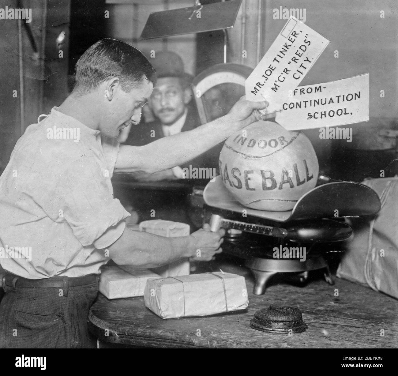 Le ballon de médecine étant pesé par l'employé de poste; étiquettes d'expédition lire: M. Joe Tinker, Mgr Reds (Cincinnati) de la continuation School Banque D'Images