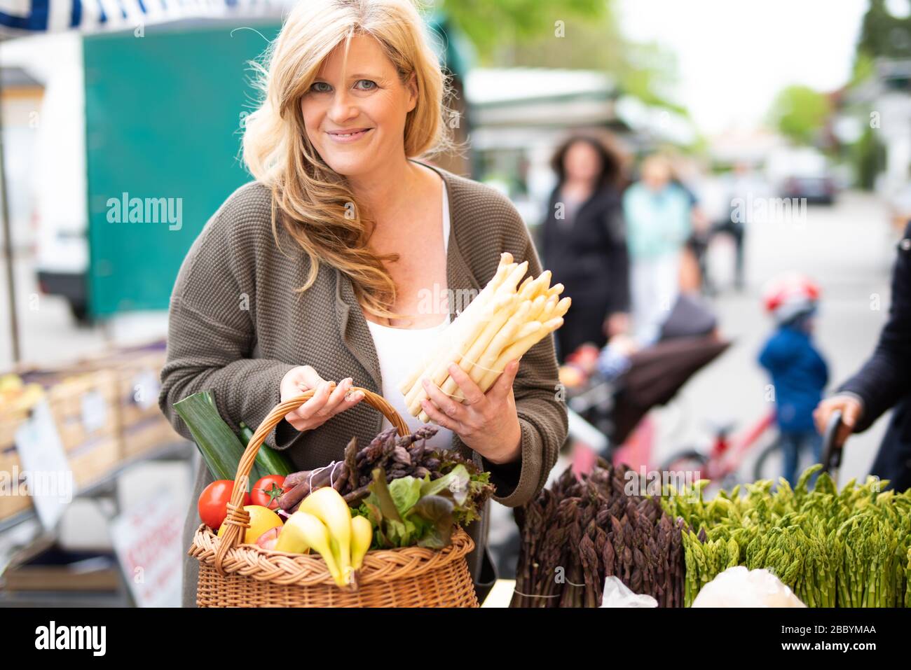 Une femme d'âge moyen achète des asperges à un marché hebdomadaire, saison des asperges Banque D'Images