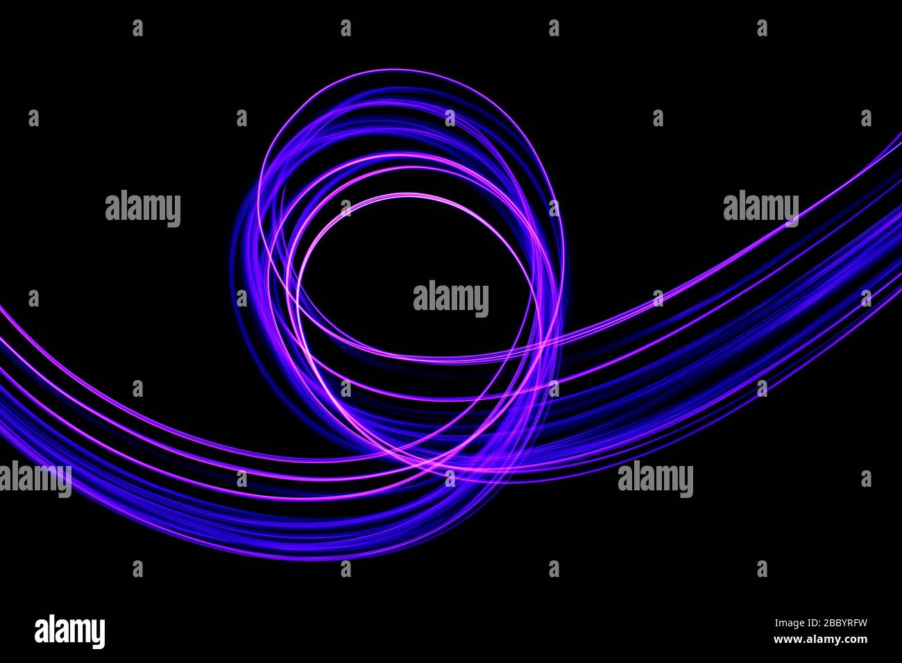 Photographie en exposition longue de couleur violet fluo dans un tourbillon abstrait, lignes parallèles sur fond noir. Photographie de peinture légère. Banque D'Images