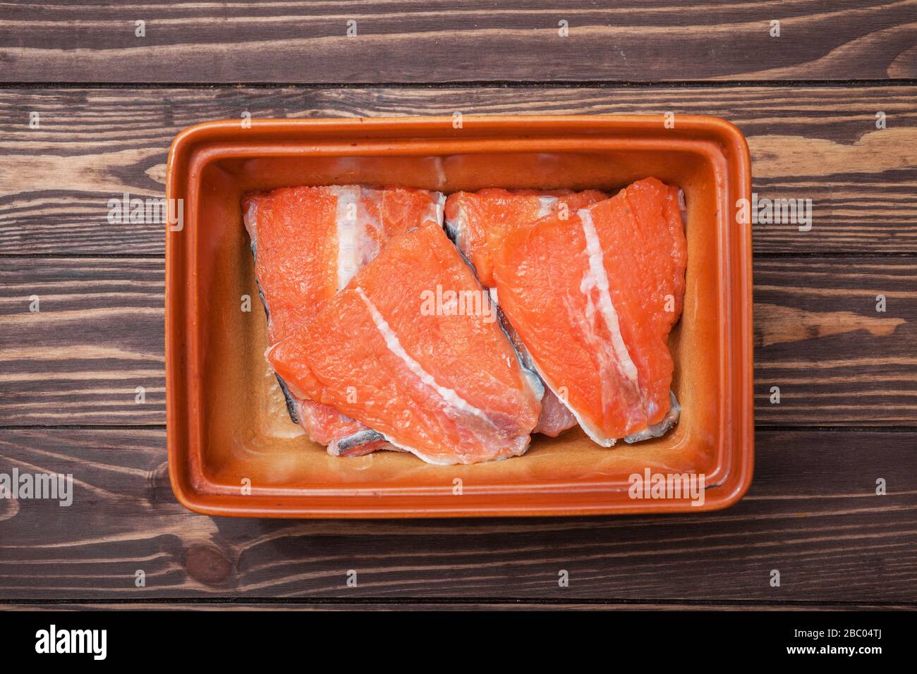 Steaks marinés de poisson rouge. Dans un bol en céramique sur des planches en bois. Prise de vue de dessus. Banque D'Images