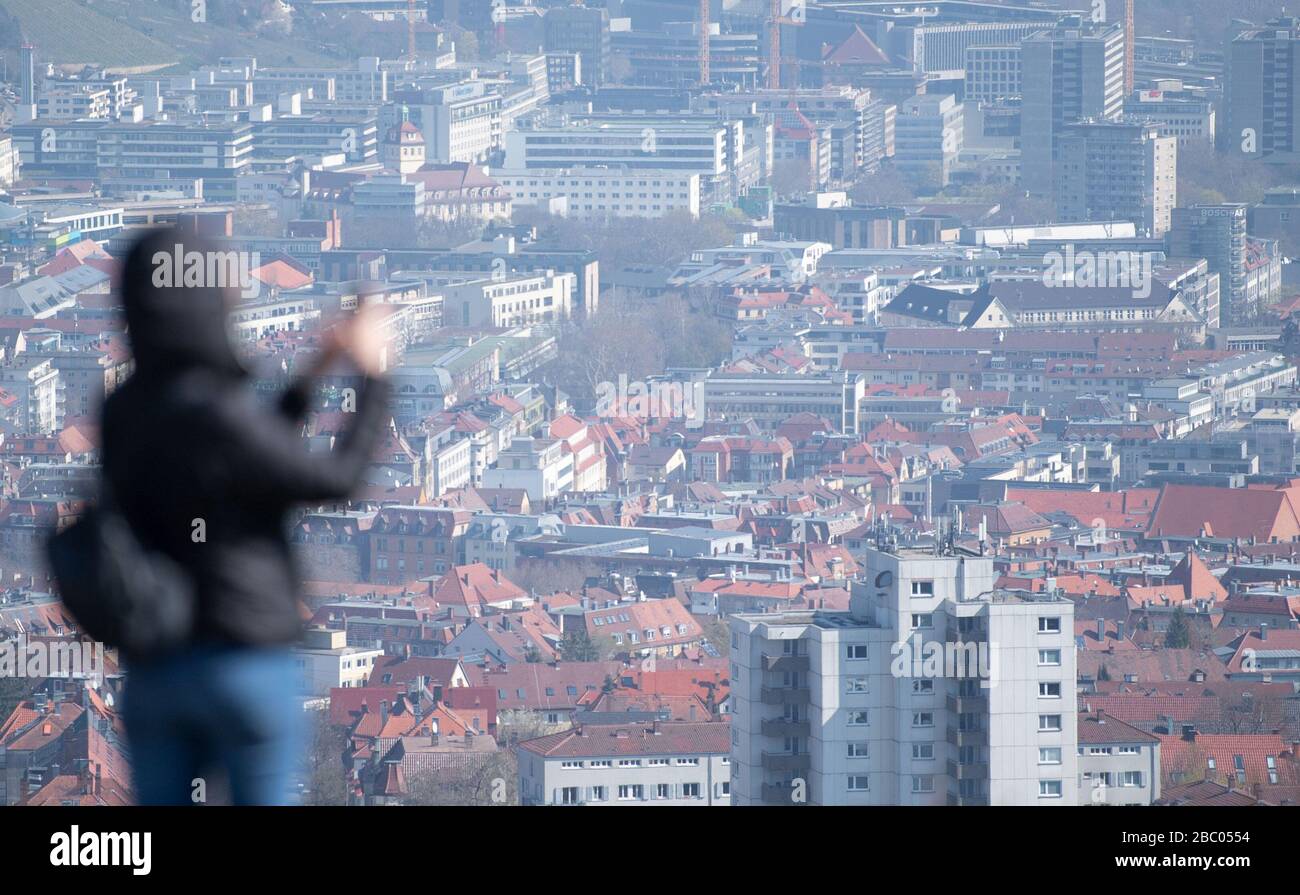 Stuttgart, Allemagne. 02 avril 2020. Une femme se tient debout avec son smartphone sur Birkenkopf et regarde la vue sur le centre-ville. Plus de 15 000 000 mètres cubes de décombres ont été déposés sur la colline après la seconde Guerre mondiale. La montagne est populairement connue sous le nom de 'Morte Scherbelino'. Crédit: Marijan Murat/dpa/Alay Live News Banque D'Images