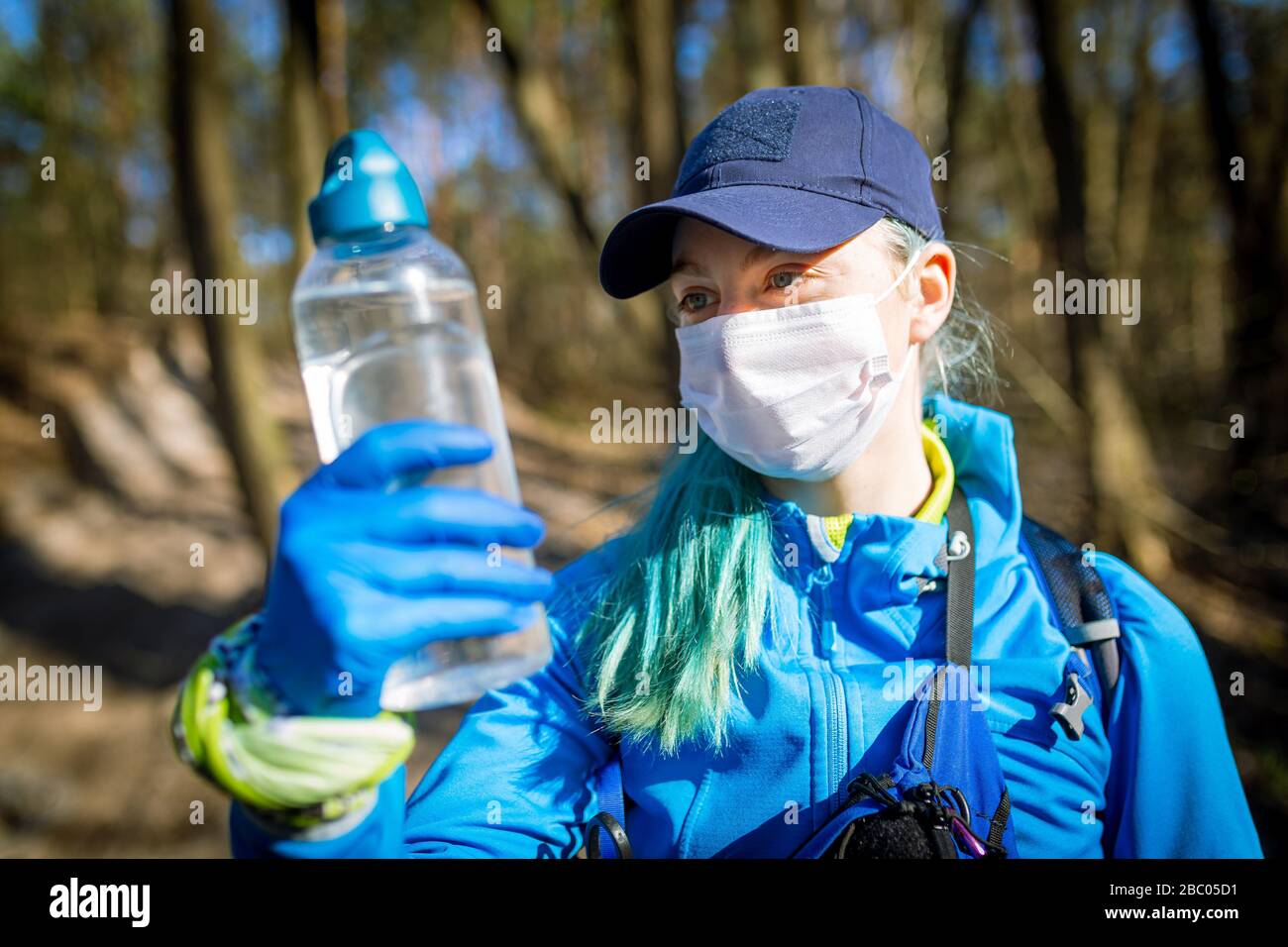 Écologiste prélever des échantillons d'eau à partir d'une source naturelle dans des gants et un masque de protection Banque D'Images