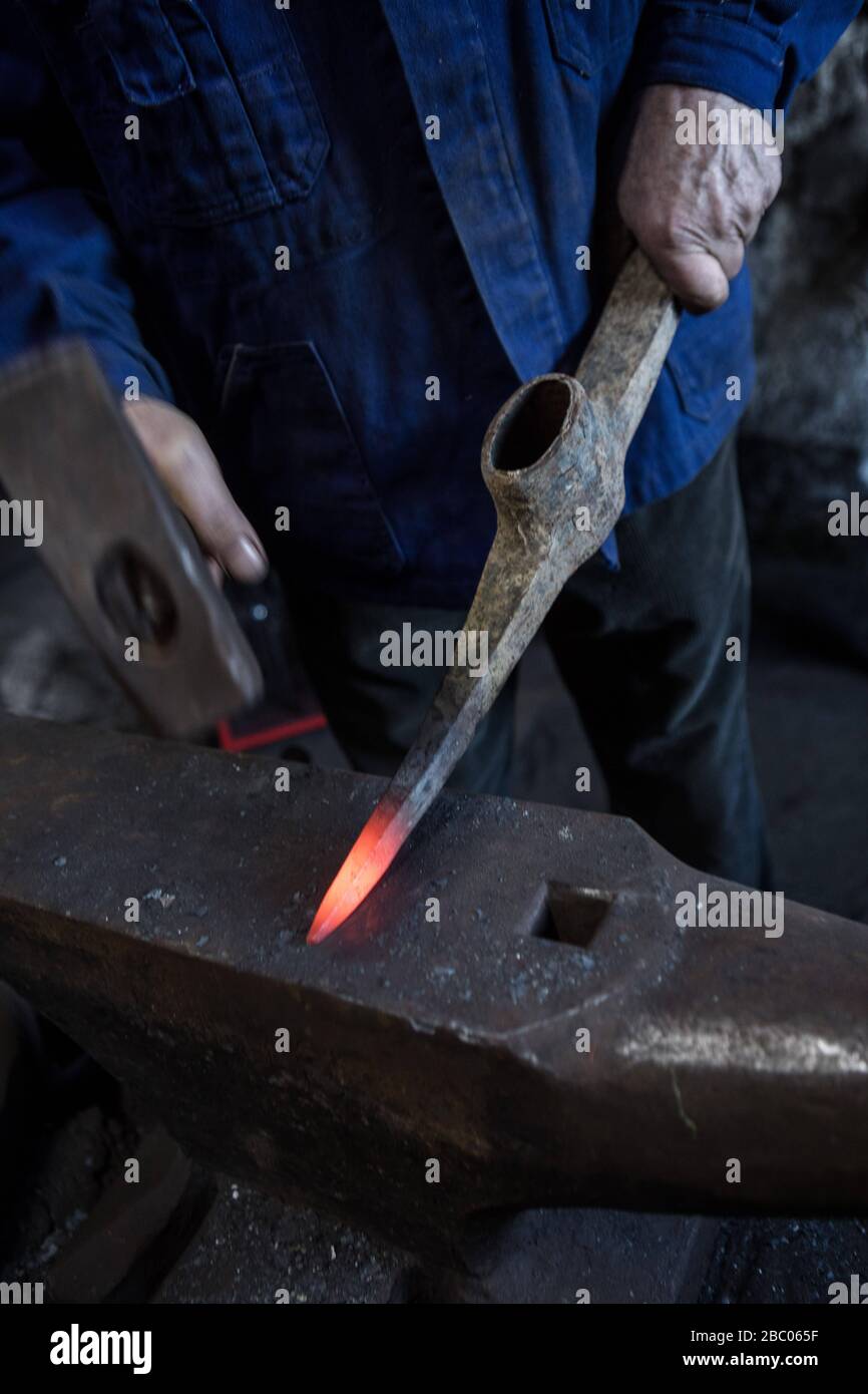 Un piquex est battu à l'enclume avec un marteau dans le smithy du Hachlschmith à Josefsthal à Schliersee. Le marteau smithy existe depuis plus de 300 ans et fournit non seulement des travailleurs forestiers régionaux et des agriculteurs forestiers, mais aussi une grande entreprise de construction avec des outils. [traduction automatique] Banque D'Images