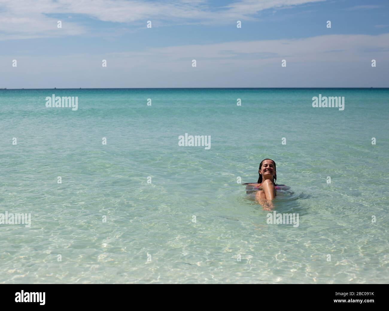 Une femme se détend dans la mer tropicale bleu clair de Koh Rong, au Cambodge. Banque D'Images