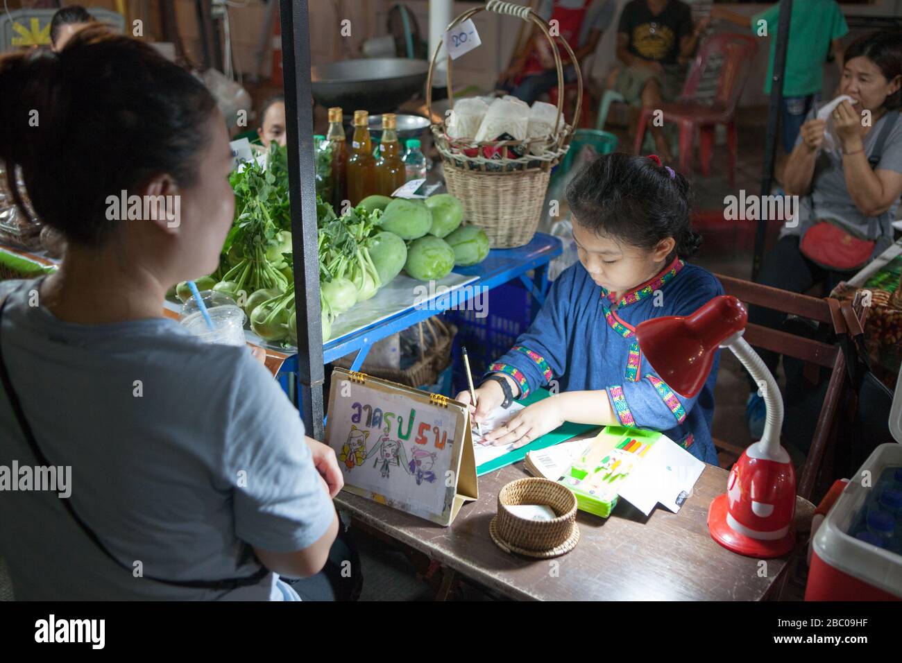 Marché de nuit et Cour alimentaire dans le centre de la ville de Chiang Rai. Il se compose de nombreux petits pieds bordant la rue étroite. Jeune fille dessine un modèle. Banque D'Images