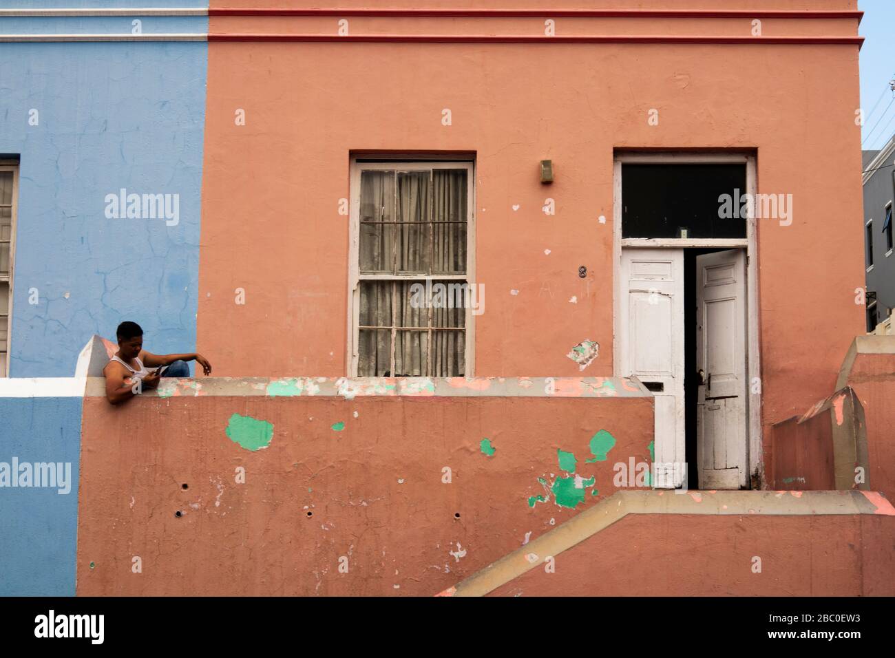 Afrique du Sud, le Cap, Schotsche Knoof, Bo Kaap, Wale St, l'homme s'est assis sur le feu de la maison non restaurée Banque D'Images